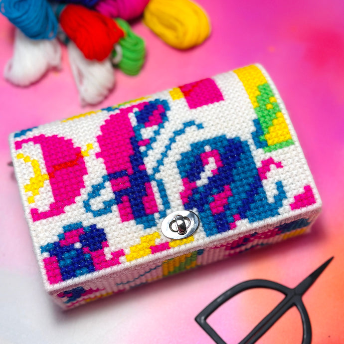 Colorful cross-stitched clutch bag with a lock on a multicolored background